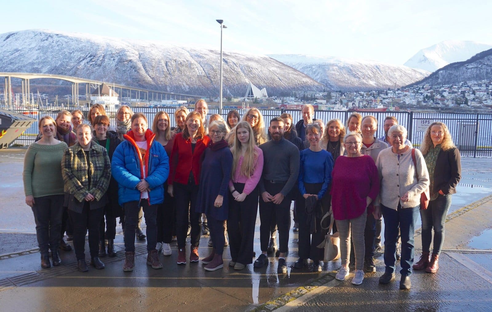 Oppstilt bilde med mange deltakere på Involvertseminaret. Tromsøbrua, fjell og kirke i bakgrunnen. Foto